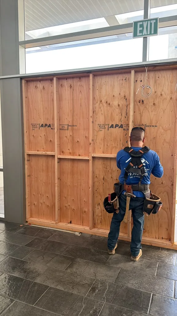 Crew member beside timber board-up at a commercial entrance