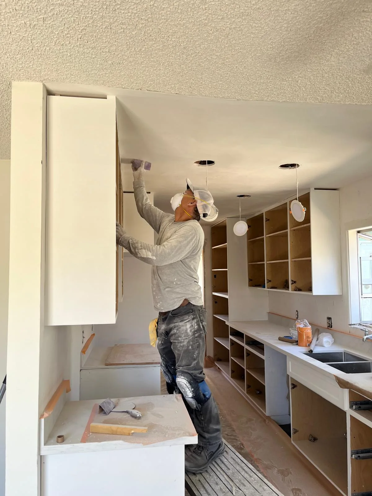 Installer working on an upper kitchen cabinet